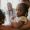 Portrait of young girl held in adult's arms while looking at camera in clinic setting with caregivers visible in background, displaying calm and serene expression